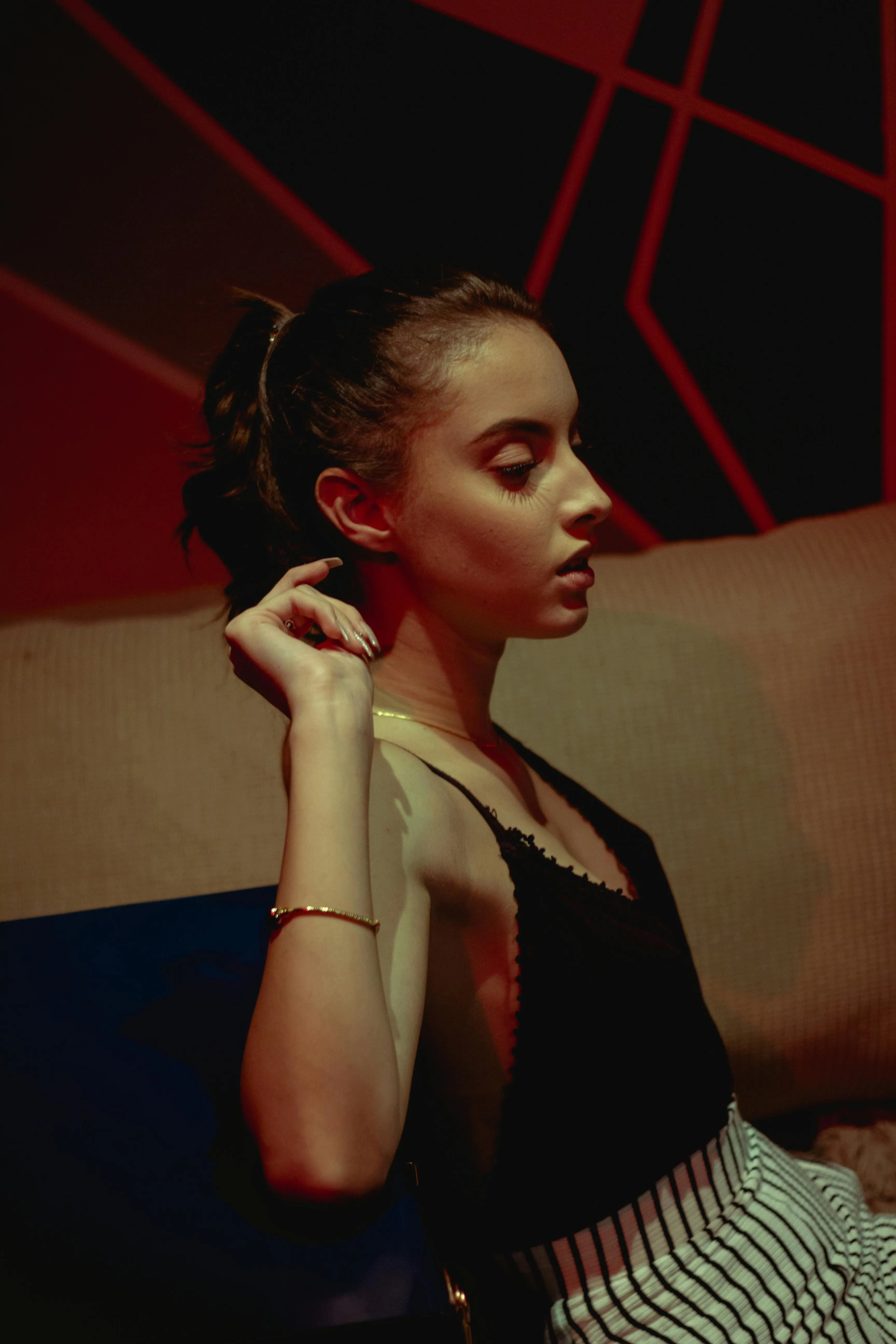Woman in an Elegant Black Dress Posing Under Red Lights