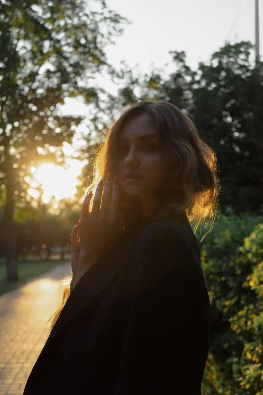 Woman in black dress walking at sunset with golden backlight