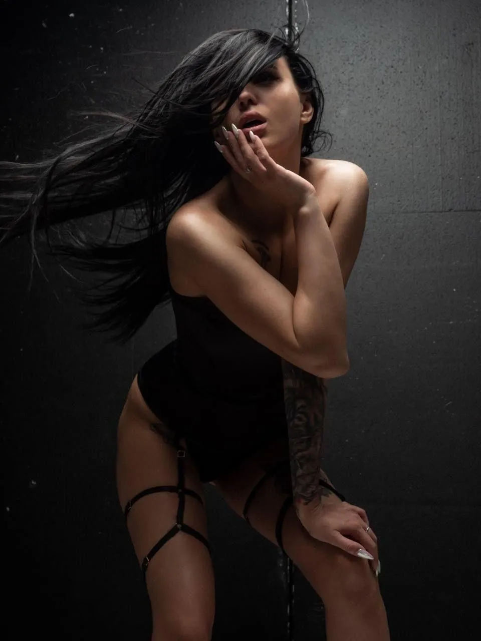 Woman in black lingerie posing dramatically with wind effect