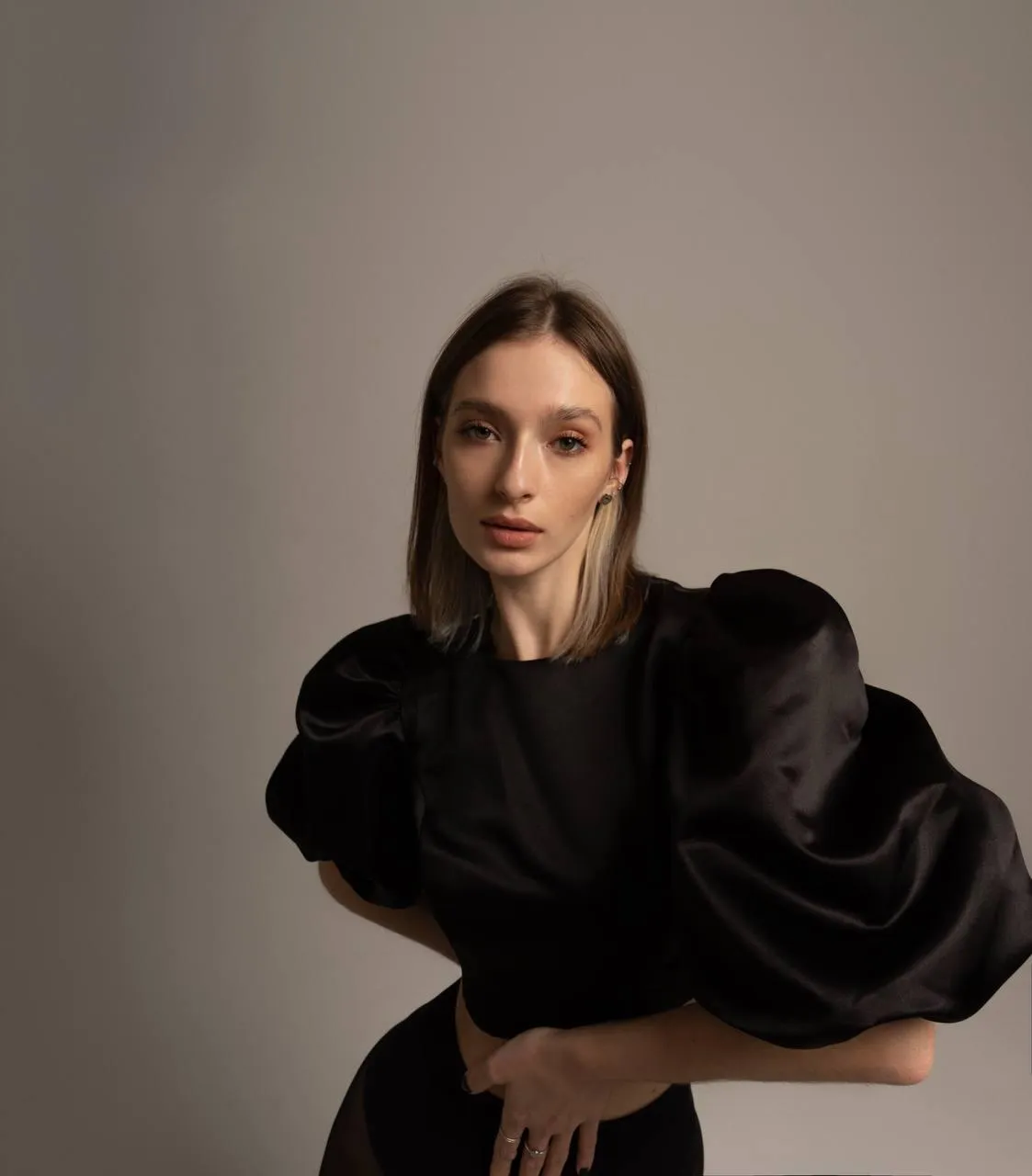 woman in black outfit standing in studio near the white wall