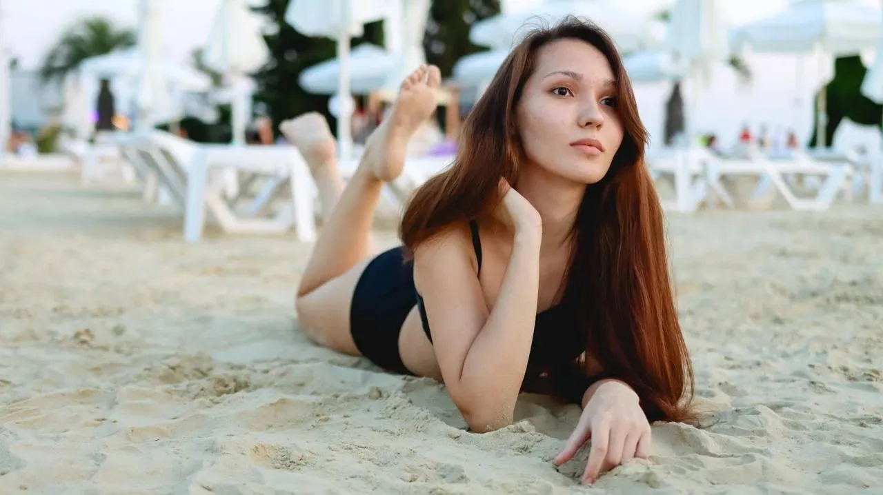 Woman in black swimsuit posing on the sand at a beach resort