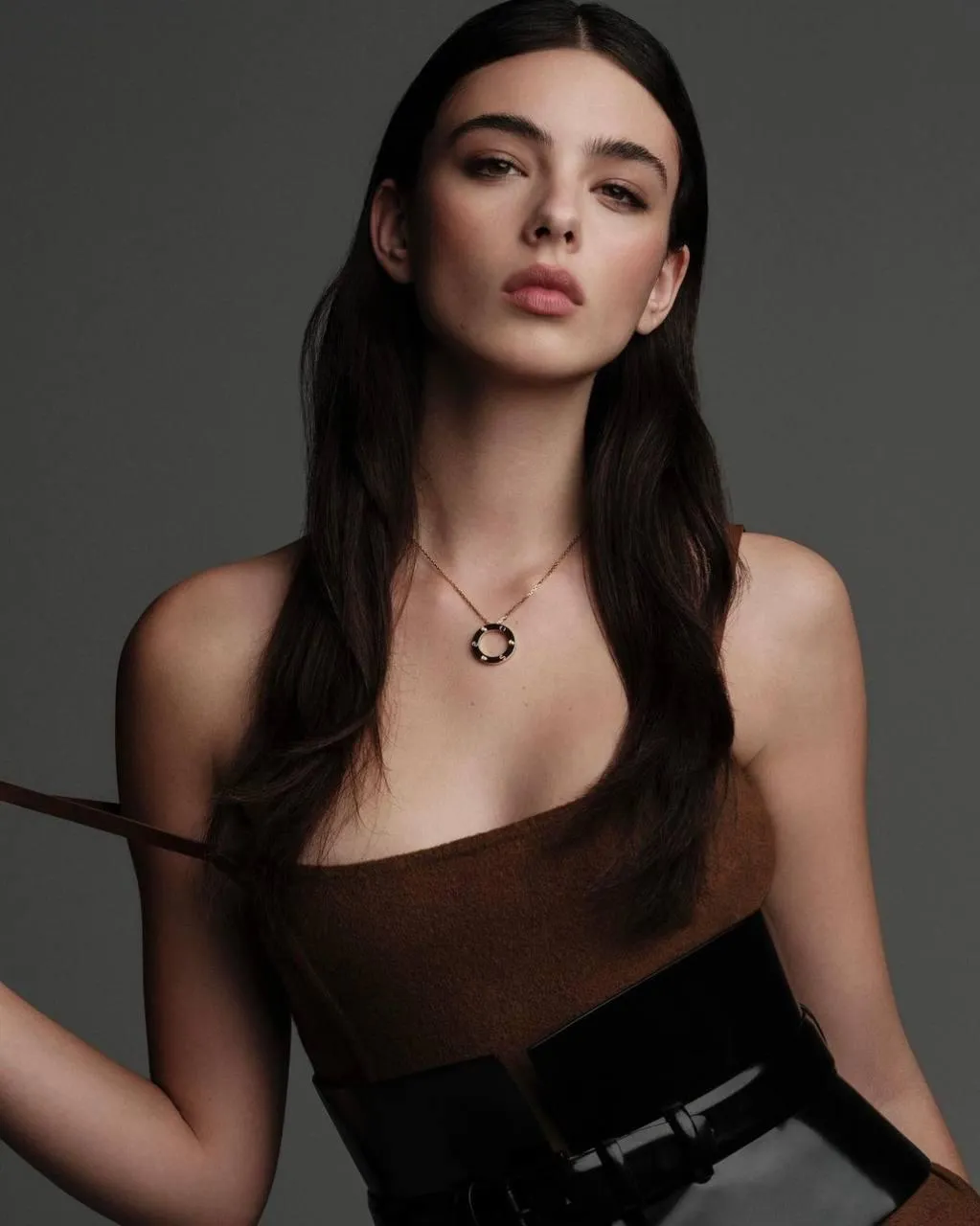 Woman in brown strapless dress posing with elegance indoors