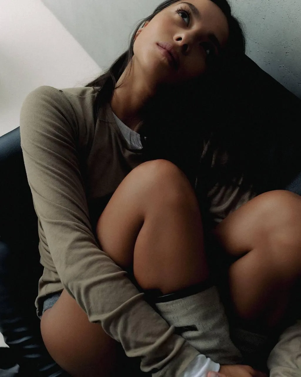 Woman in Casual Wear Sitting Indoors with Tilted Pose Image