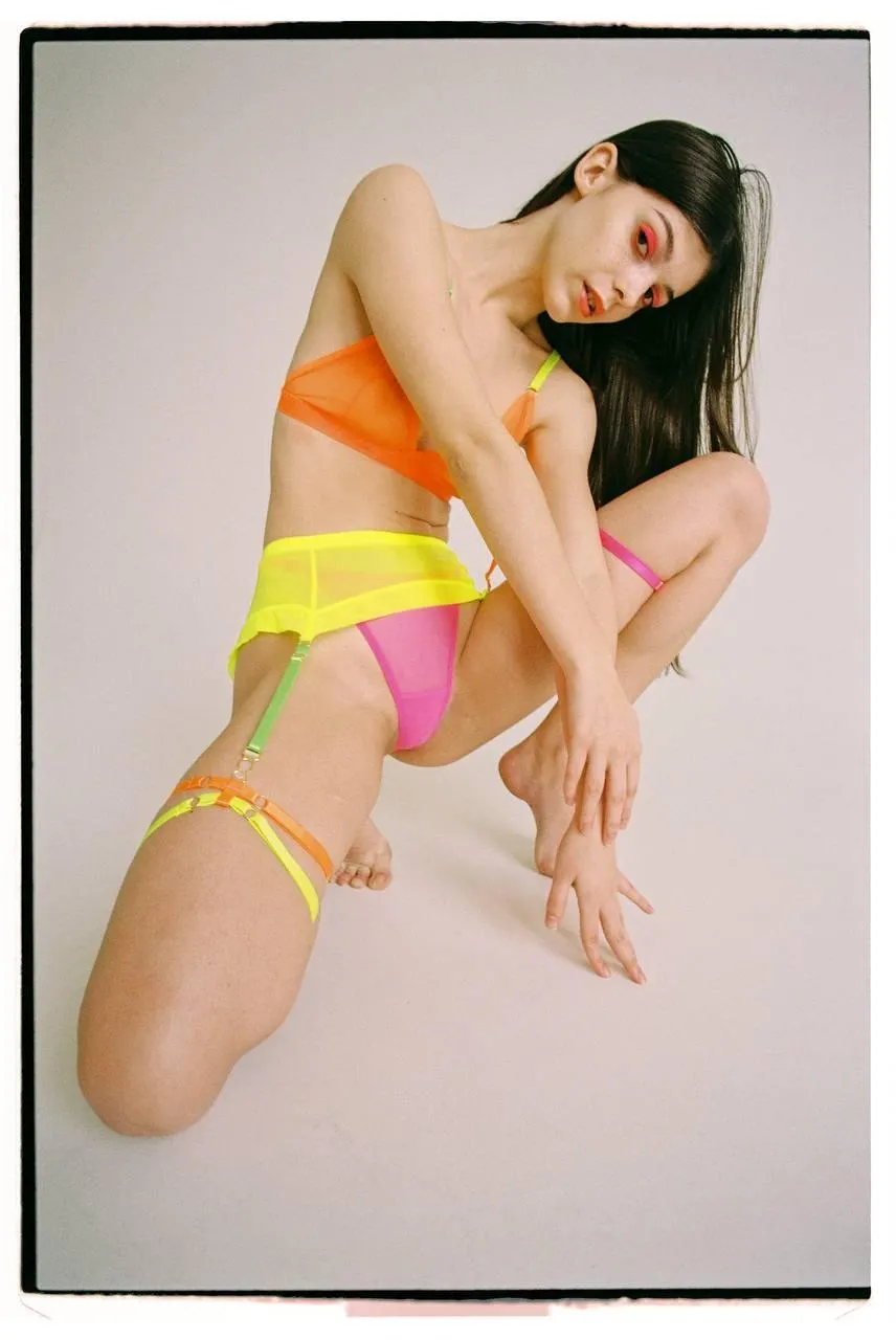 Woman in colorful lingerie posing against studio background