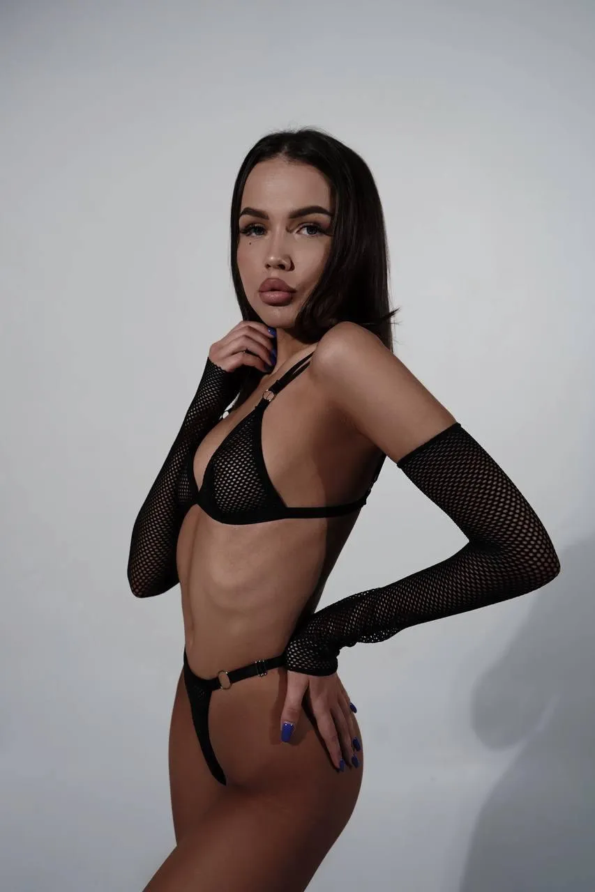 Woman in lingerie posing confidently against a dark backdrop