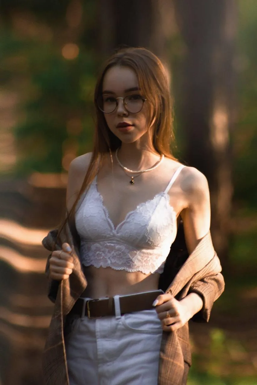 Woman in nature wearing a tank top and jeans in golden light