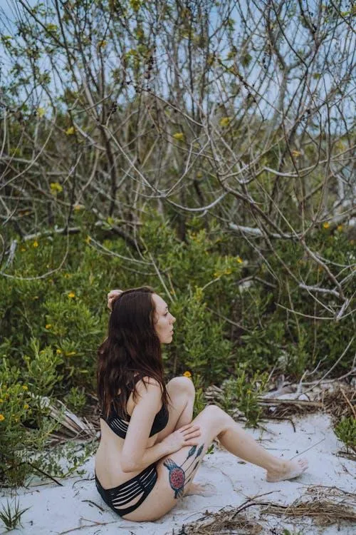 Woman in nature wearing lingerie sitting near dry trees
