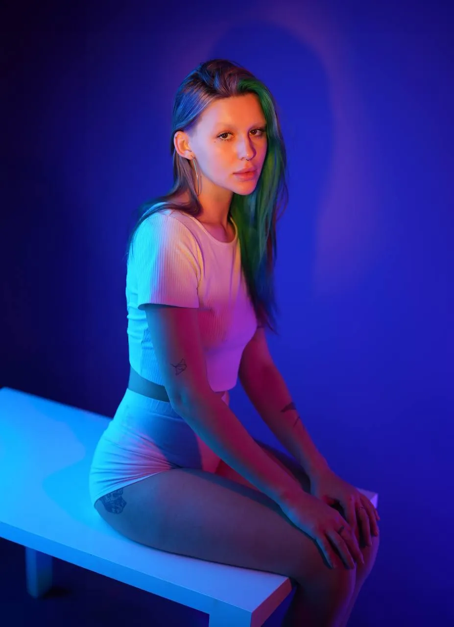 Woman in neon lighting sitting on a white bench indoors