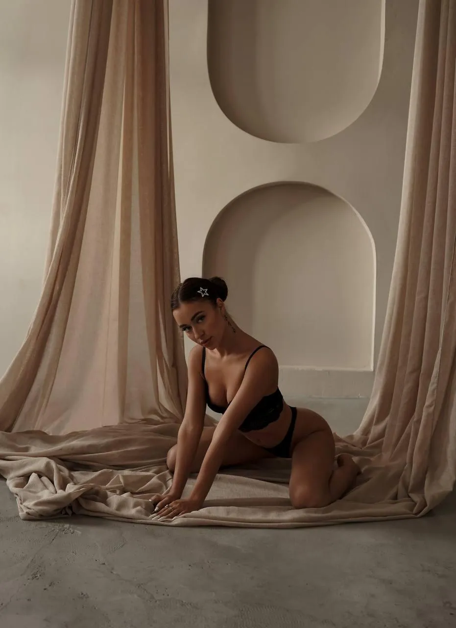 Woman in nude bodysuit posing in elegant neutral toned room