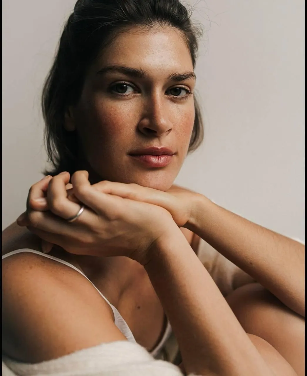 Woman in nude toned dress sits peacefully on a soft surface