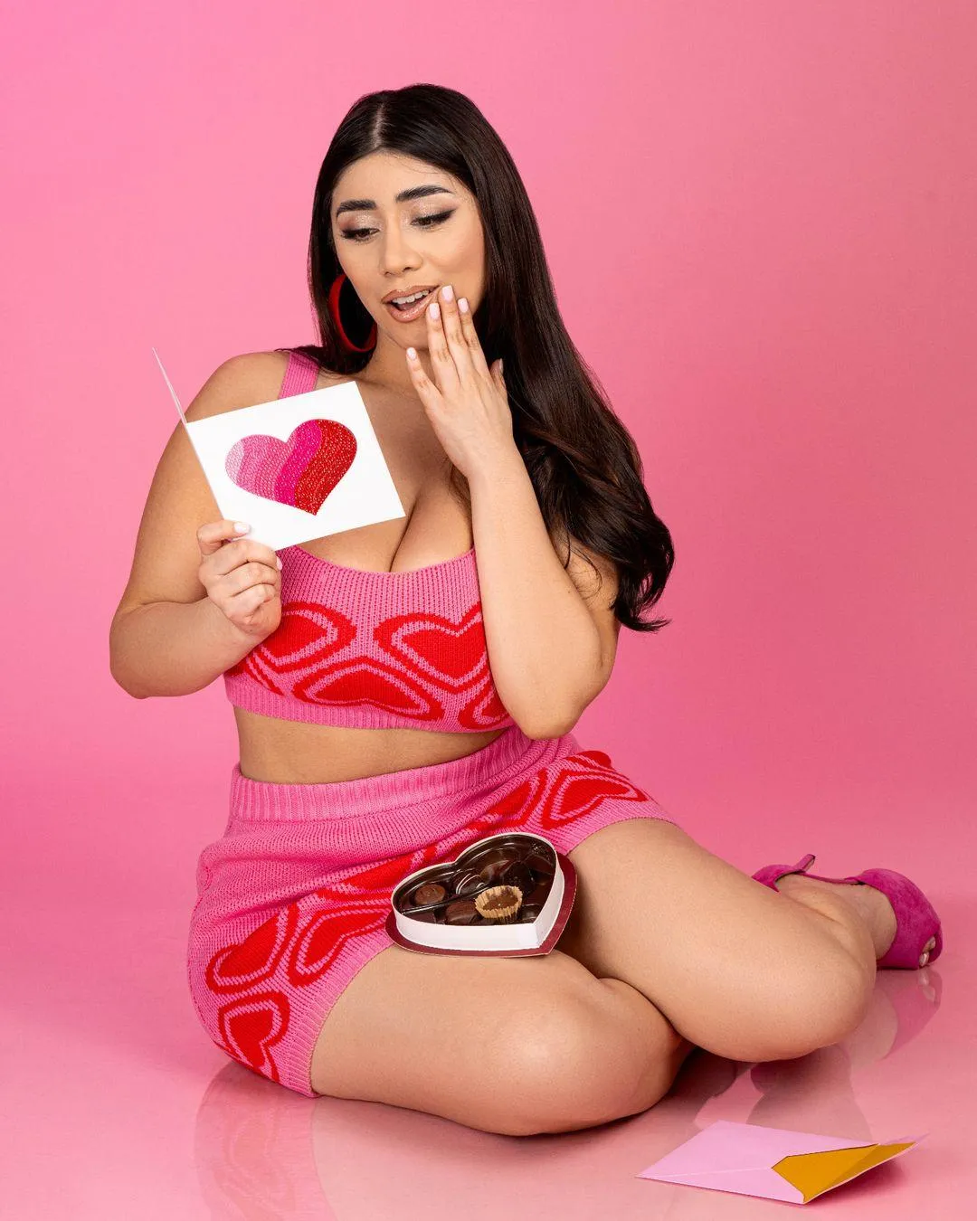 Woman in Pink Outfit Holding Chocolates with Pink Background