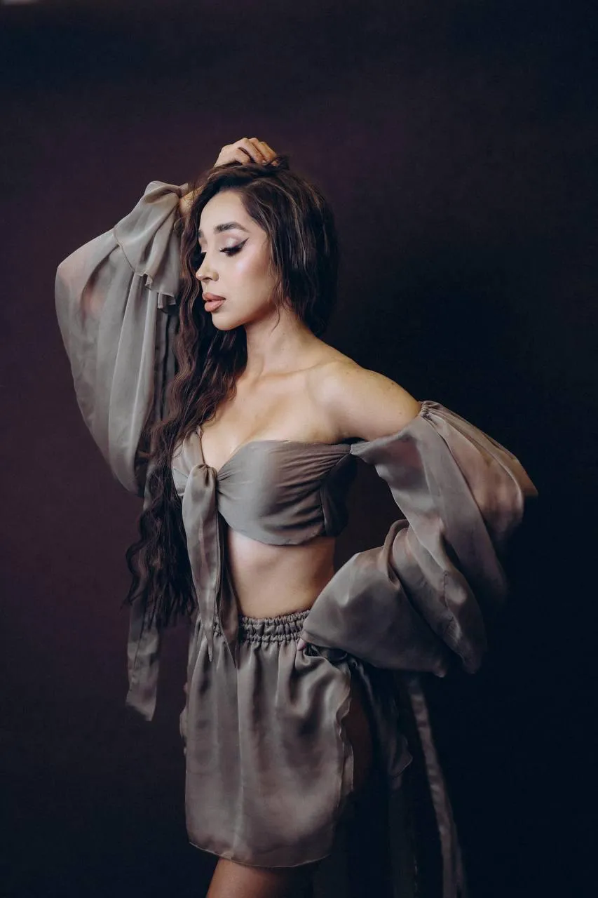 Woman in sheer robe posing gracefully against dark backdrop