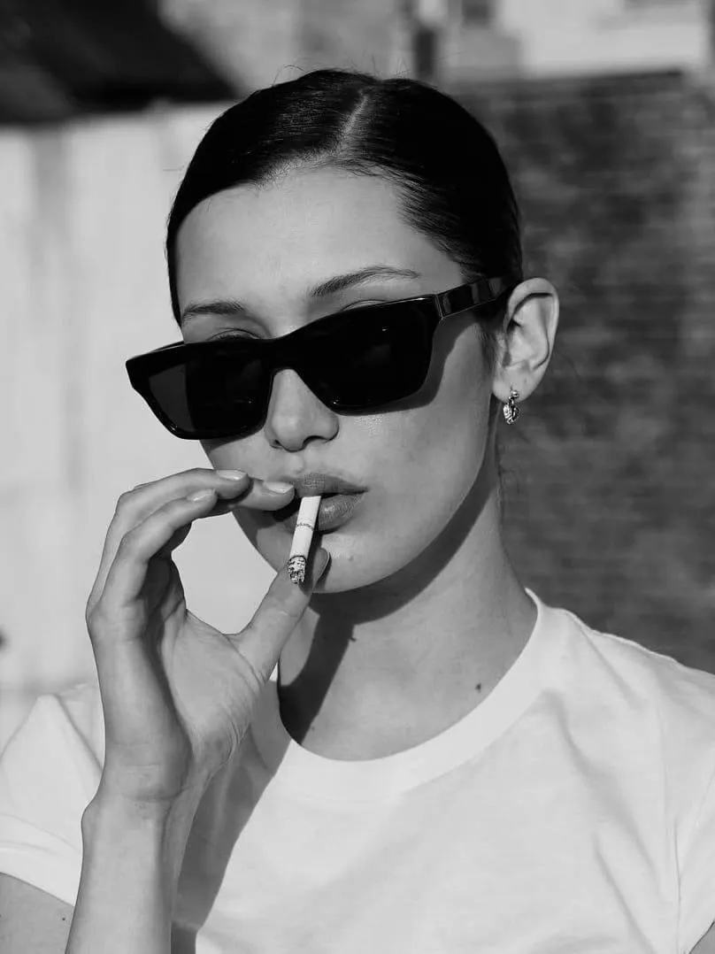 Woman in sunglasses smoking a cigarette in black and white
