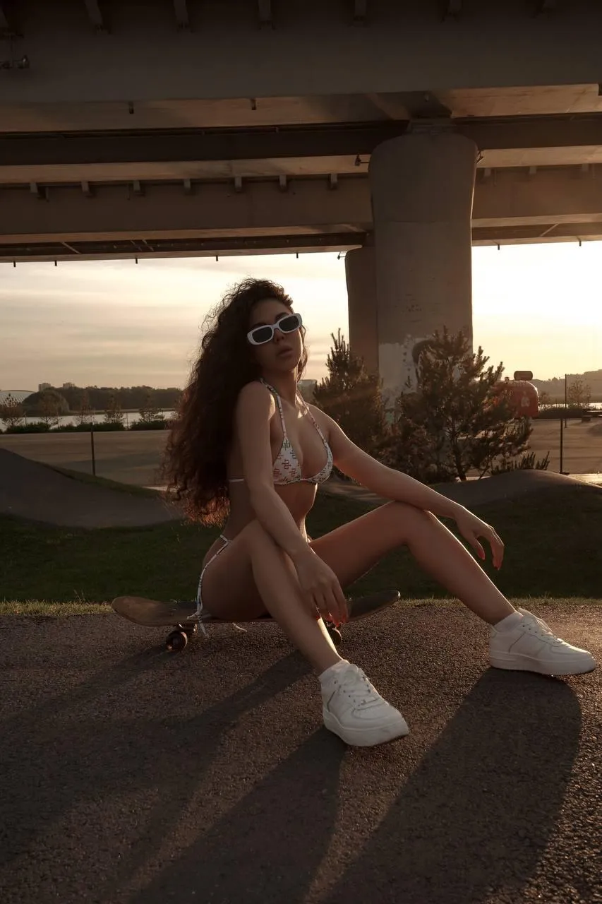 Woman in Swimwear Posing on Pavement Beneath Urban Bridge