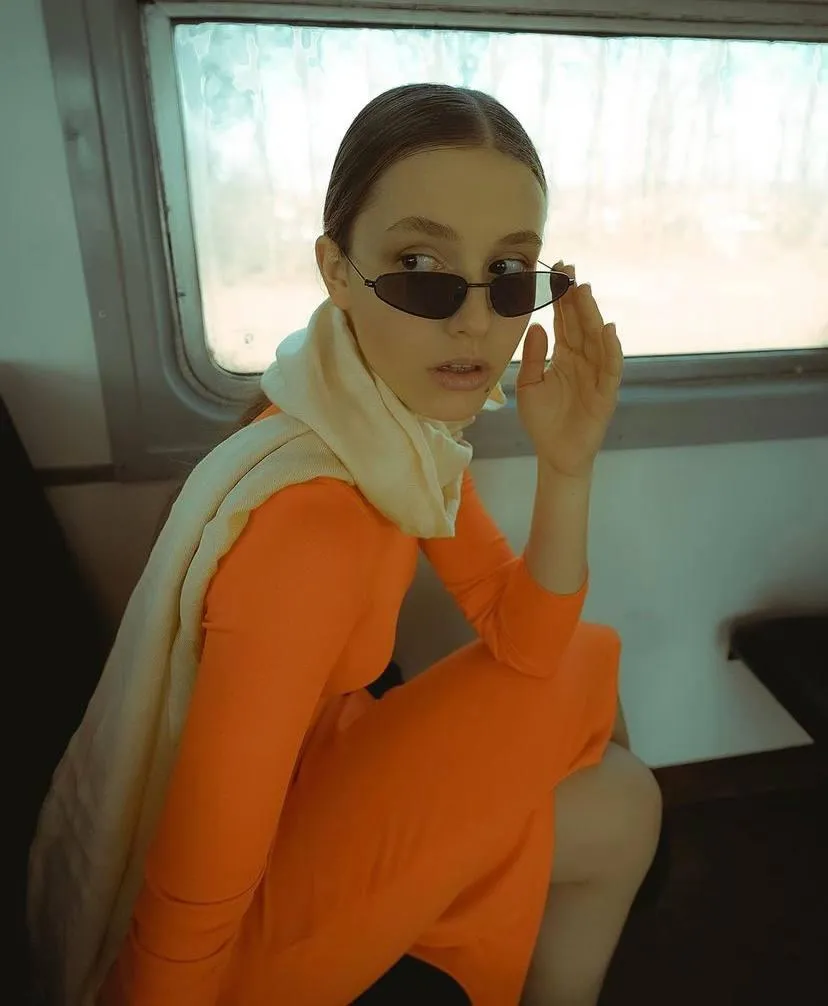 woman in the train wearing an orange dress with glasses