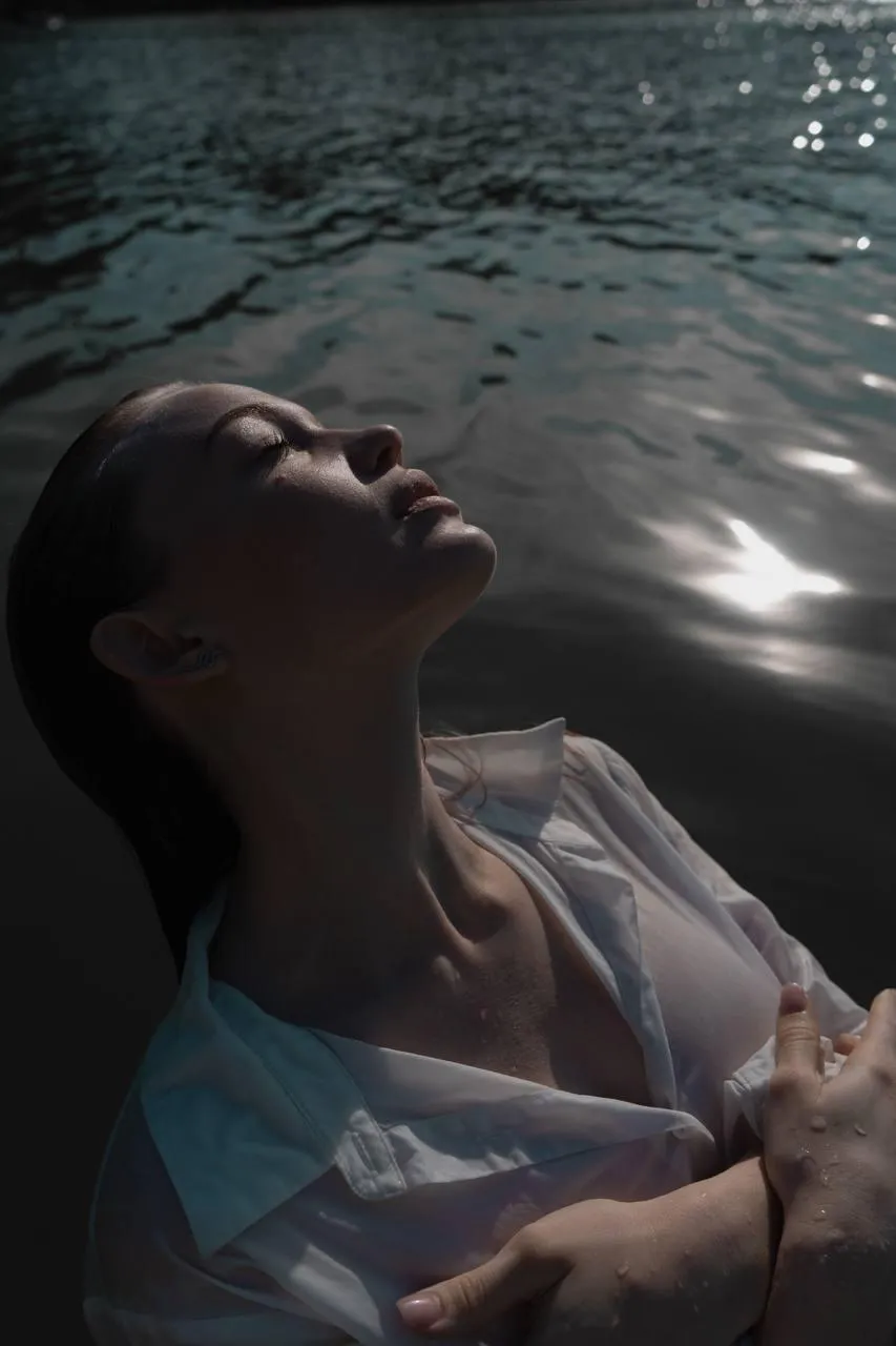 Woman in the water with dramatic light posing gracefully