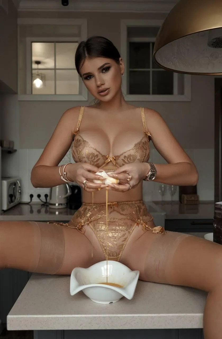 Woman in transparent bodysuit sitting on kitchen counter