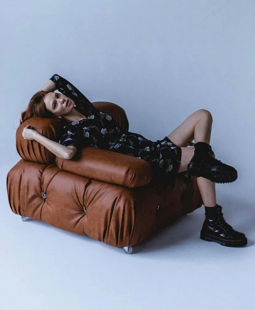 Woman lounging on a brown leather couch with a cool attitude
