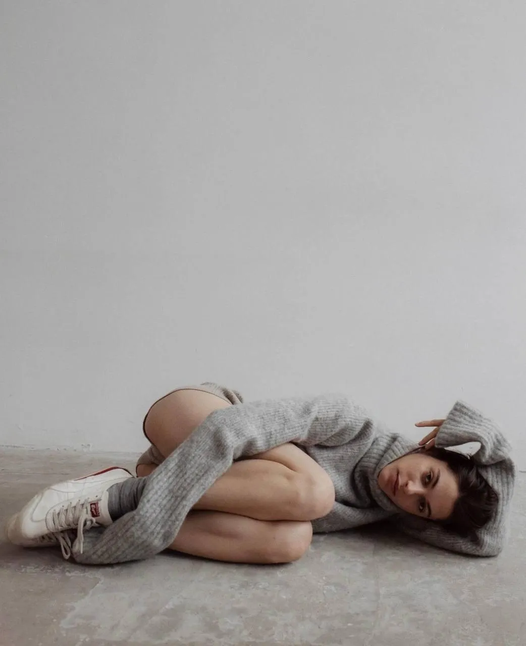 Woman lying on floor in cozy outfit with relaxed expression