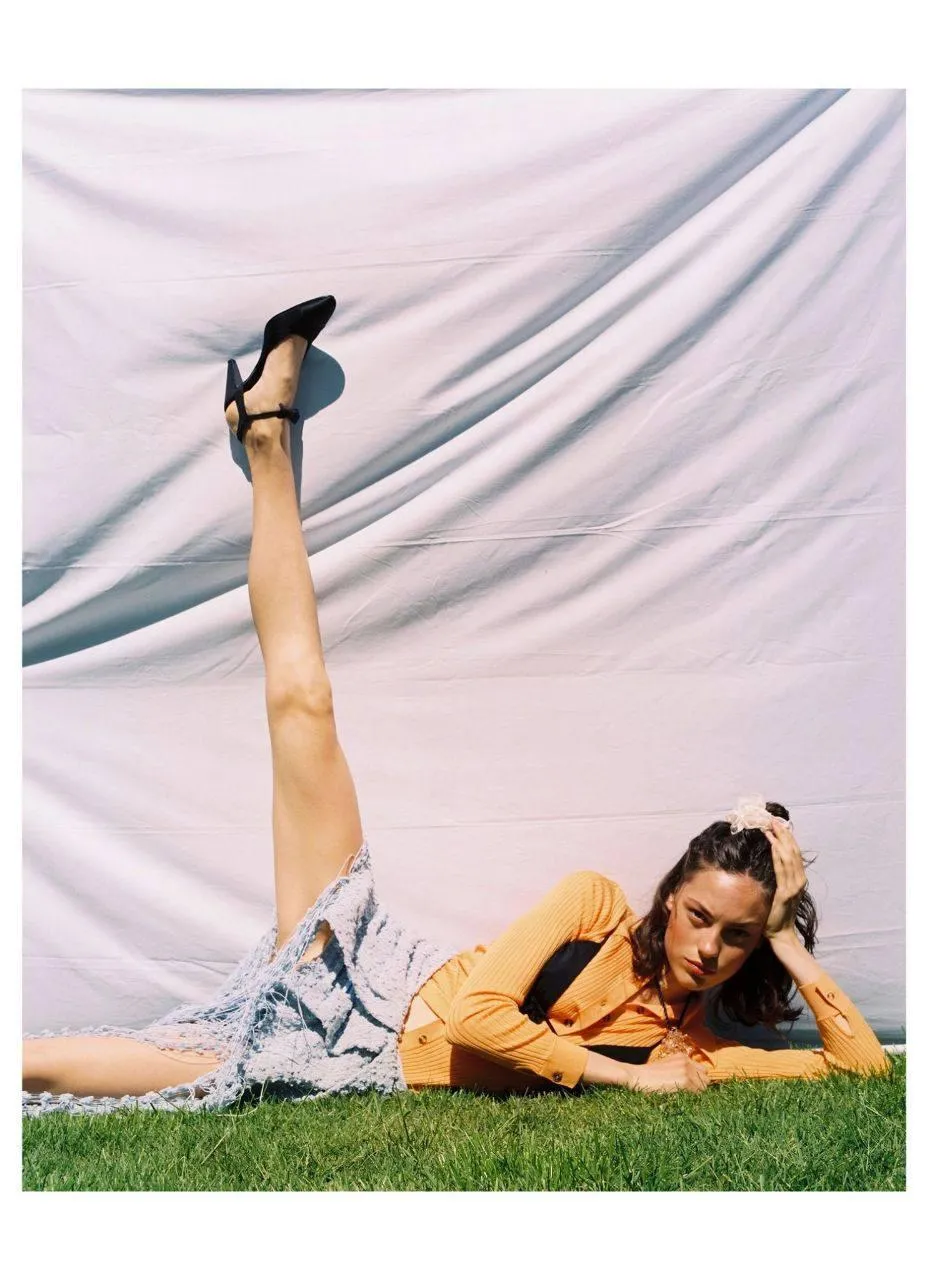 Woman Lying on Grass with Her Legs Raised in a Summer Outfit