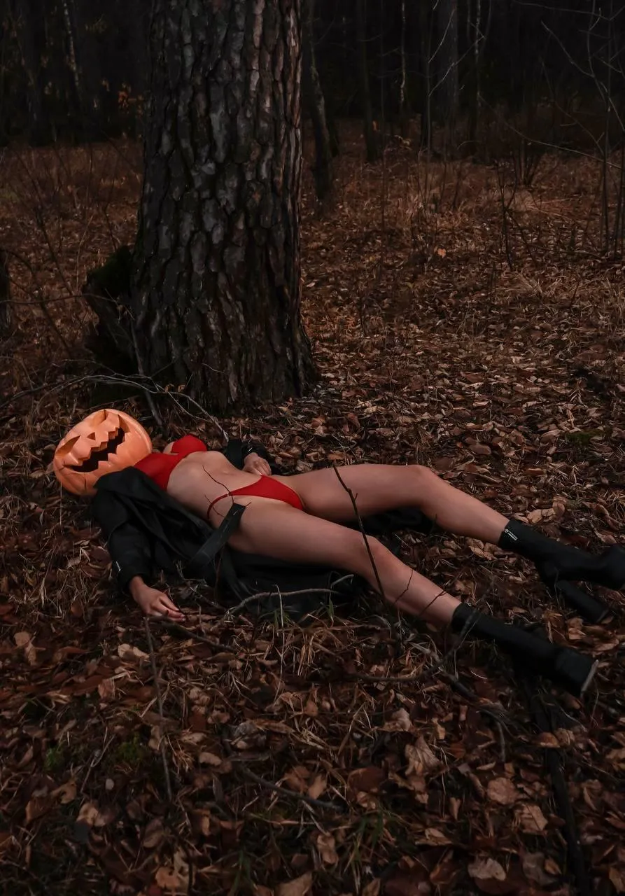 Woman Model in a Red Lying on Leaves in a Moody Forest Scene