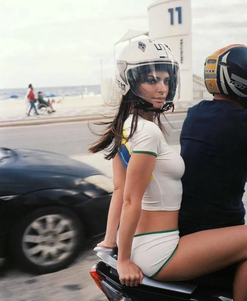 Woman on a scooter wearing a helmet and white casual outfit