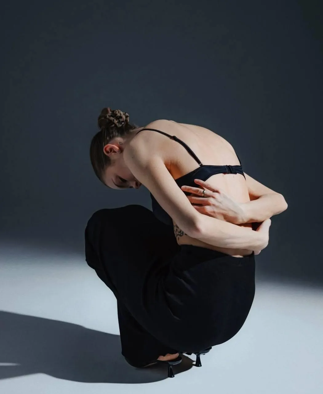 Woman on squatting on the white floor with her hand back