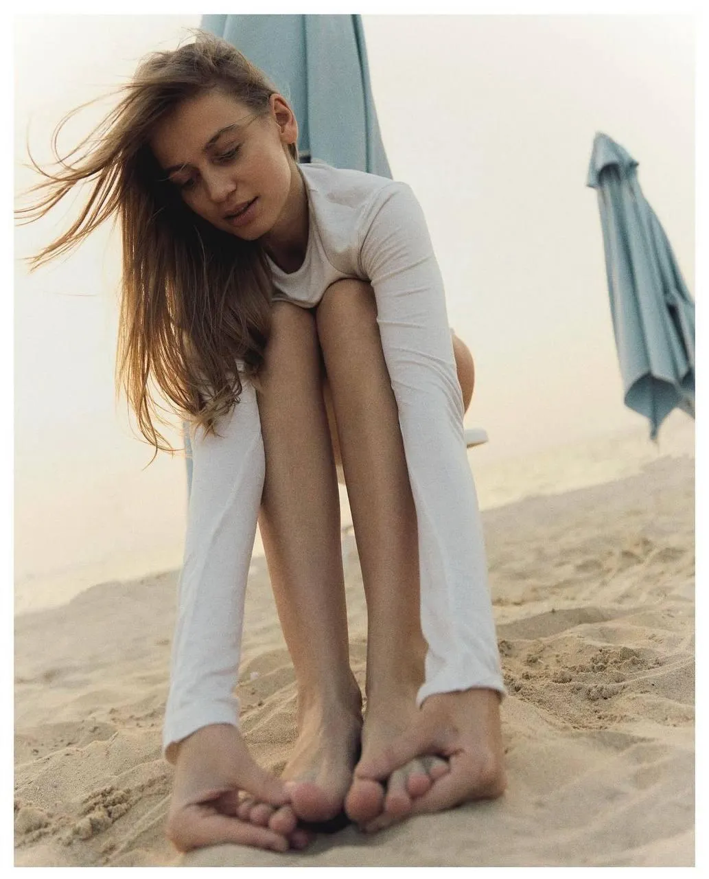 Woman on the Beach Sitting with Feet Tucked Close Wallpaper
