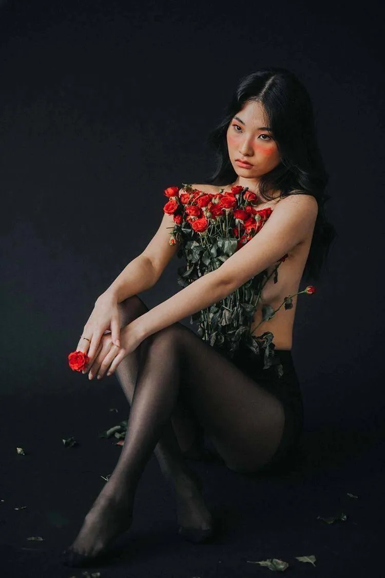 Woman posing elegantly in a floral detailed black outfit