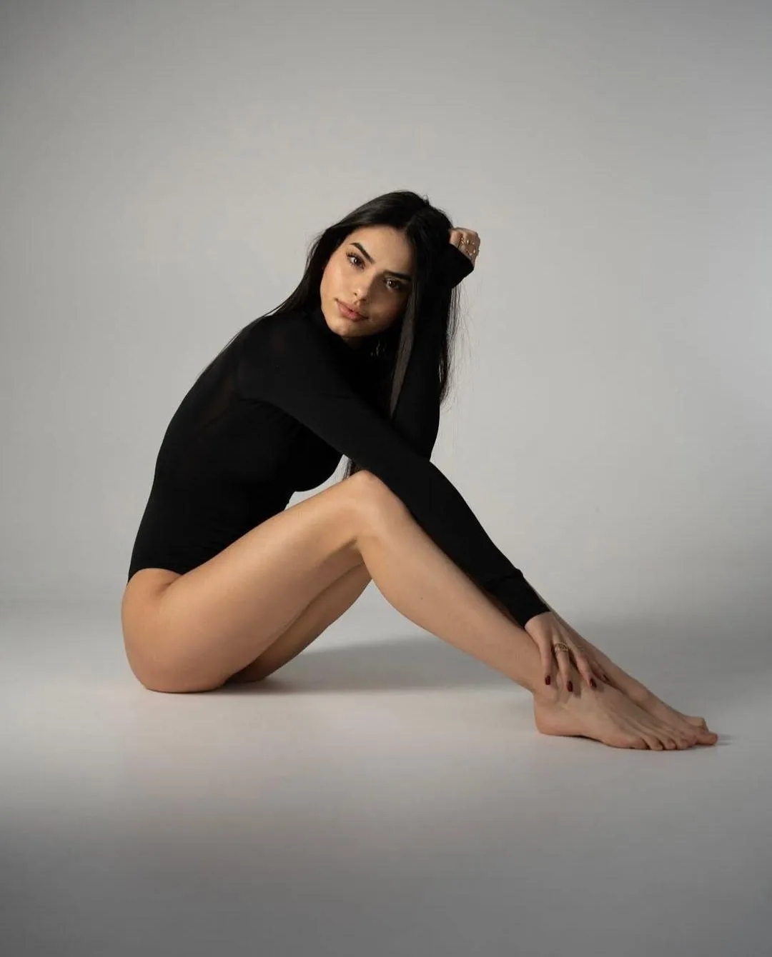 Woman posing in a black bodysuit sitting on the floor photo