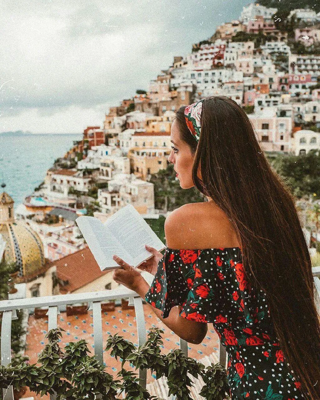 Woman Reading a Book on the Balcony Overlooking Amalfi Coast