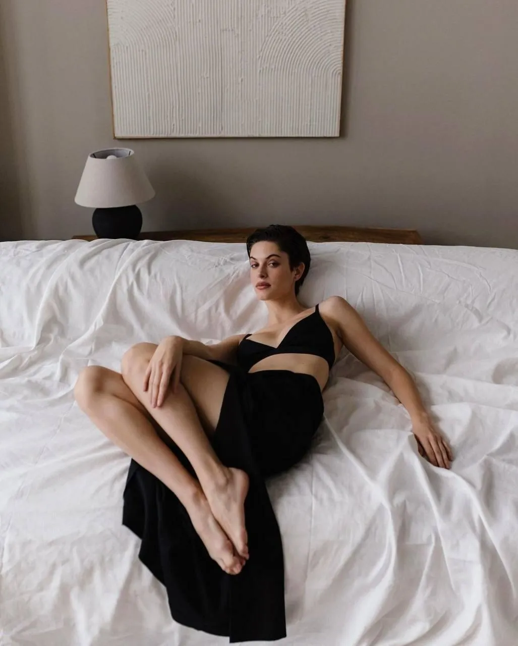 Woman Reclining on Bed in Black Dress with Elegant Posture