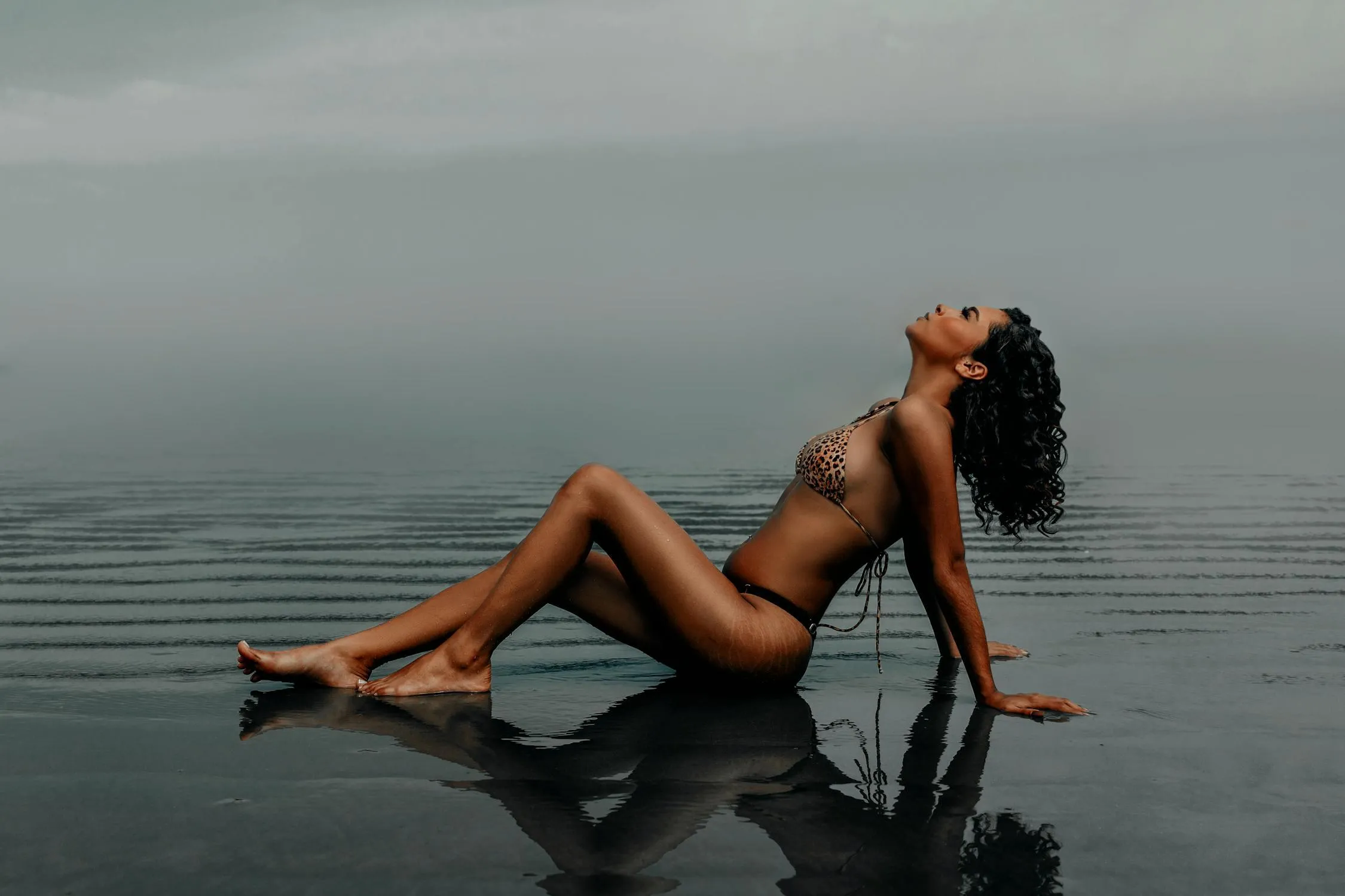 Woman Relaxes on a Dock with Her Legs in Calm Lake Water