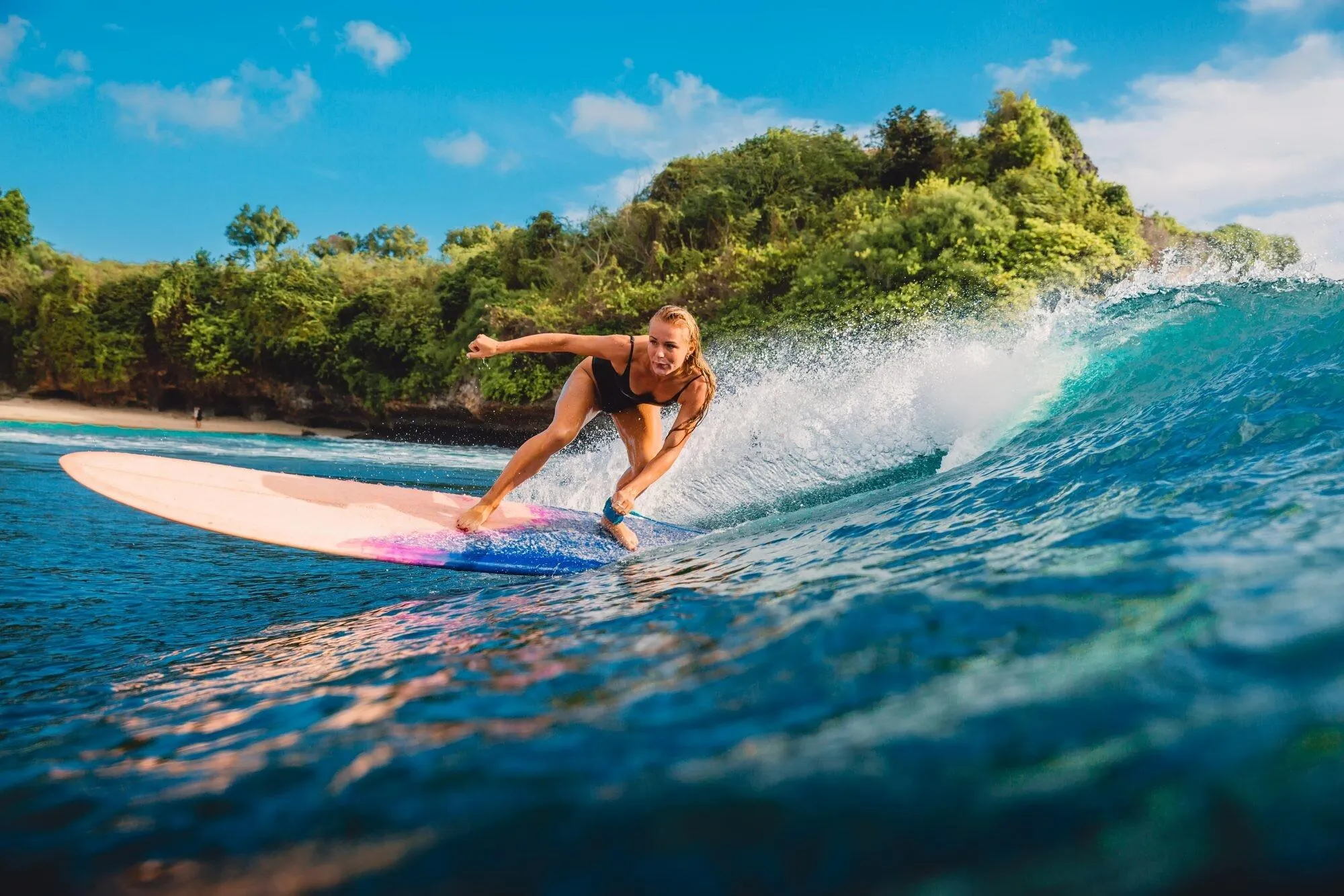 Woman Riding a Colorful Surfboard Across Clear Blue Water