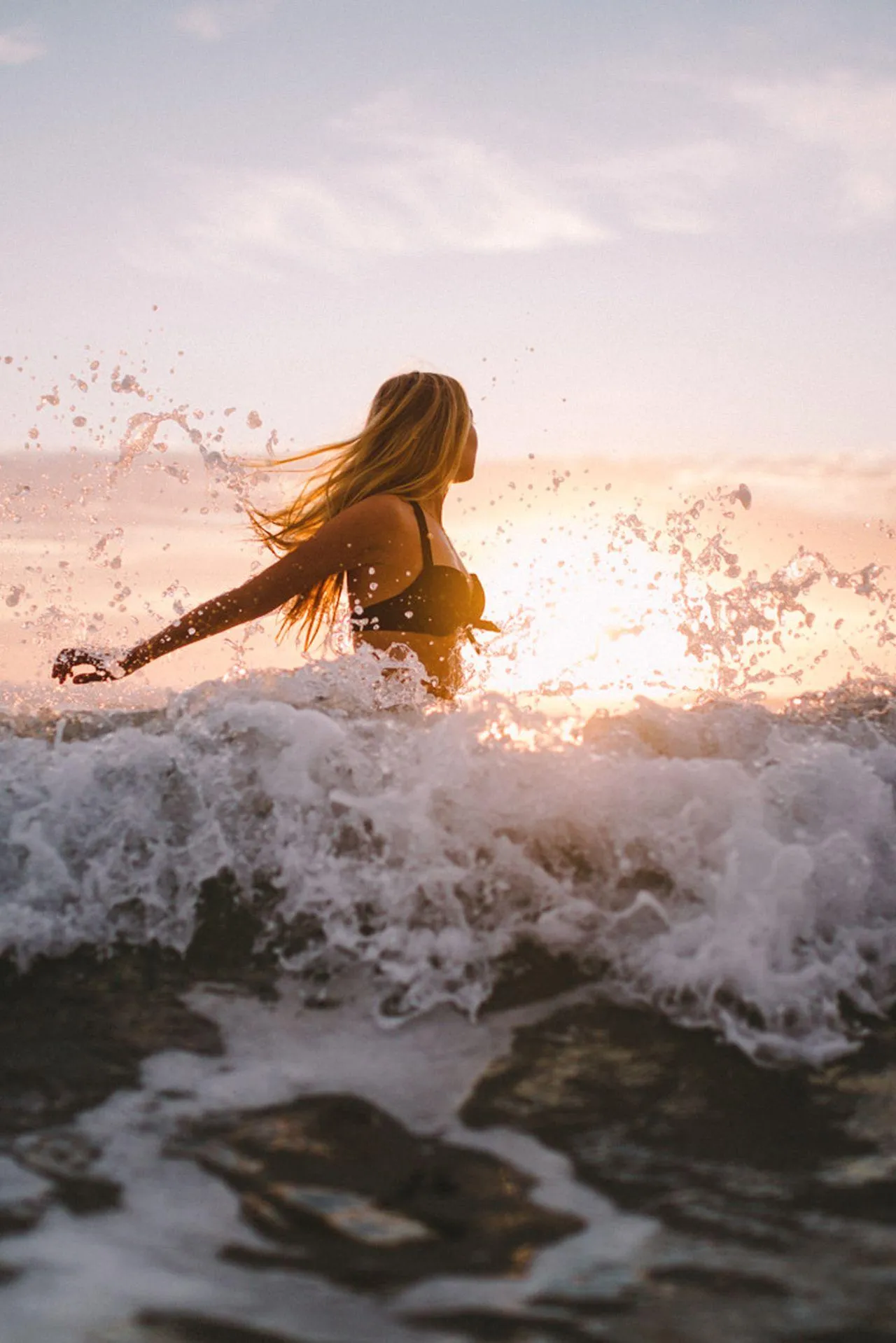 Woman Runs Into Ocean Waves During Dramatic Sunset Wallpaper