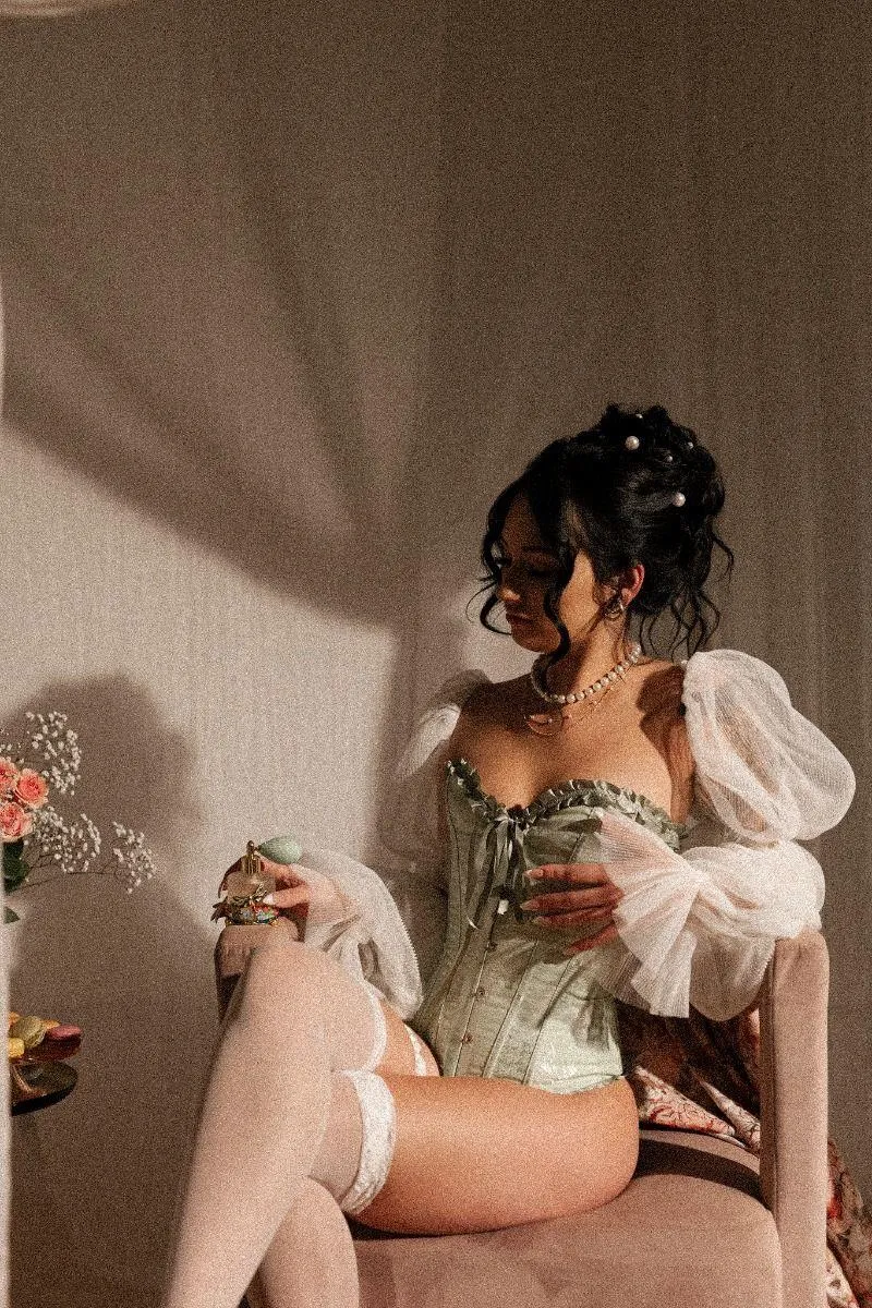 Woman Sitting in a Cozy Room Wearing a Green Corset Dress