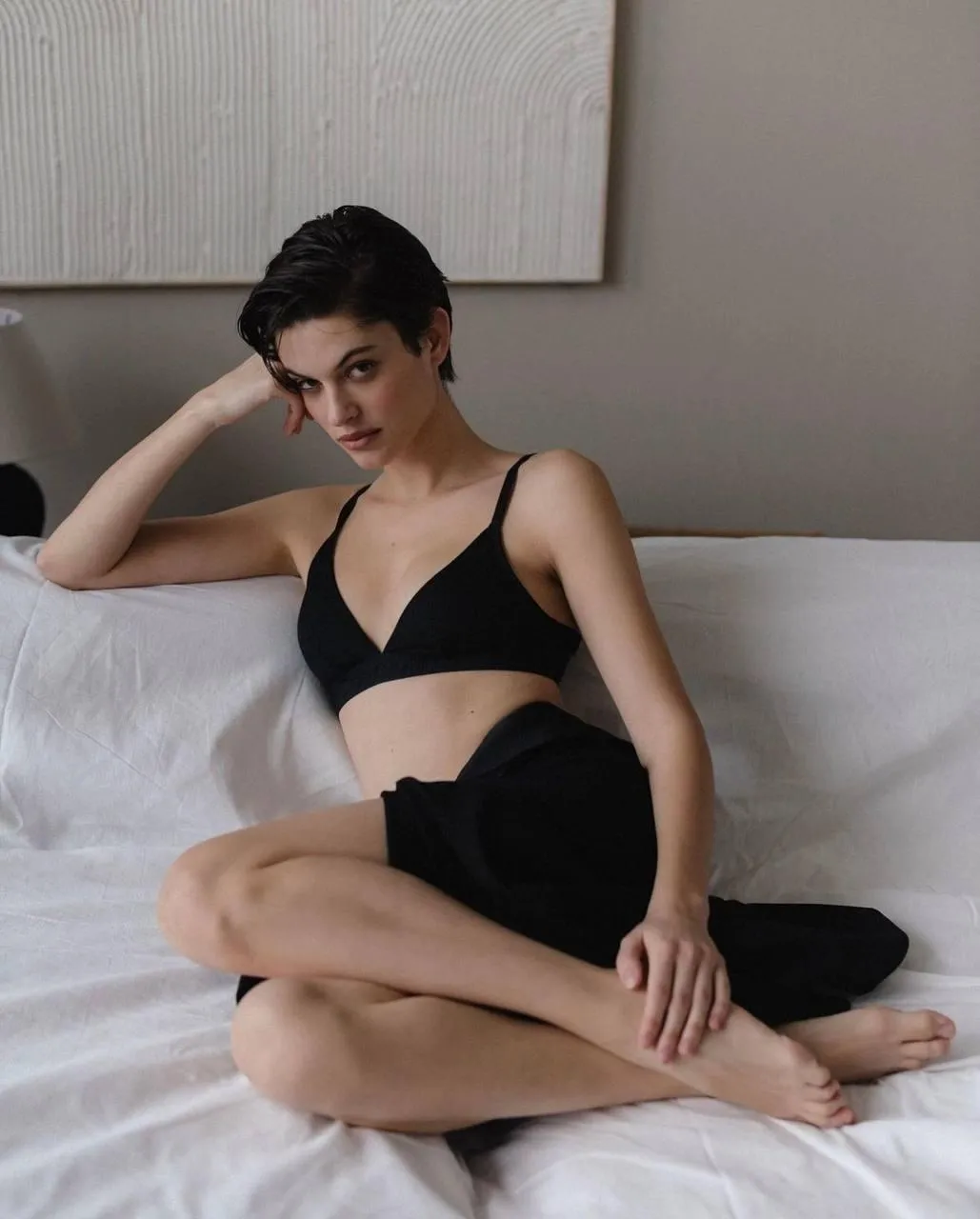 Woman Sitting on a Bed in a Black Top with a Short Hairstyle