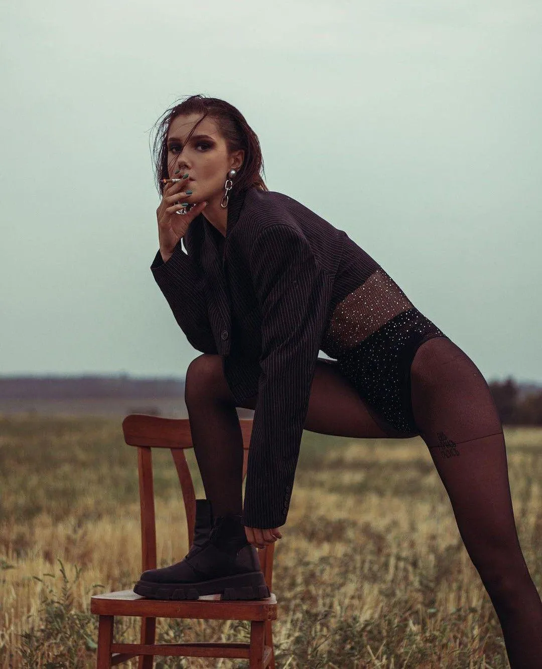 Woman Sitting on a Chair in a Field with Hand on Her Chin