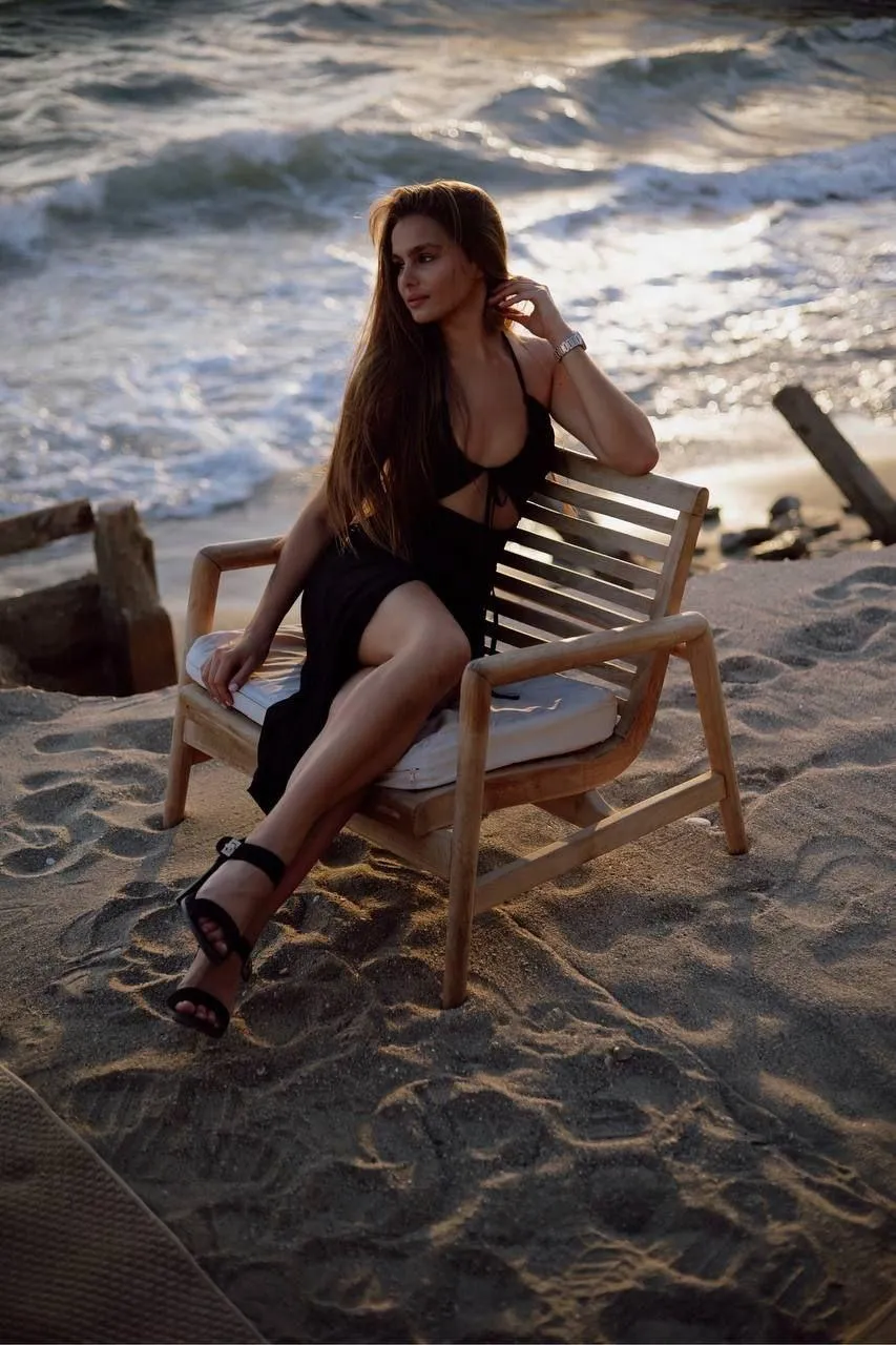 Woman Sitting on Beach Chair Near Ocean During Golden Sunset