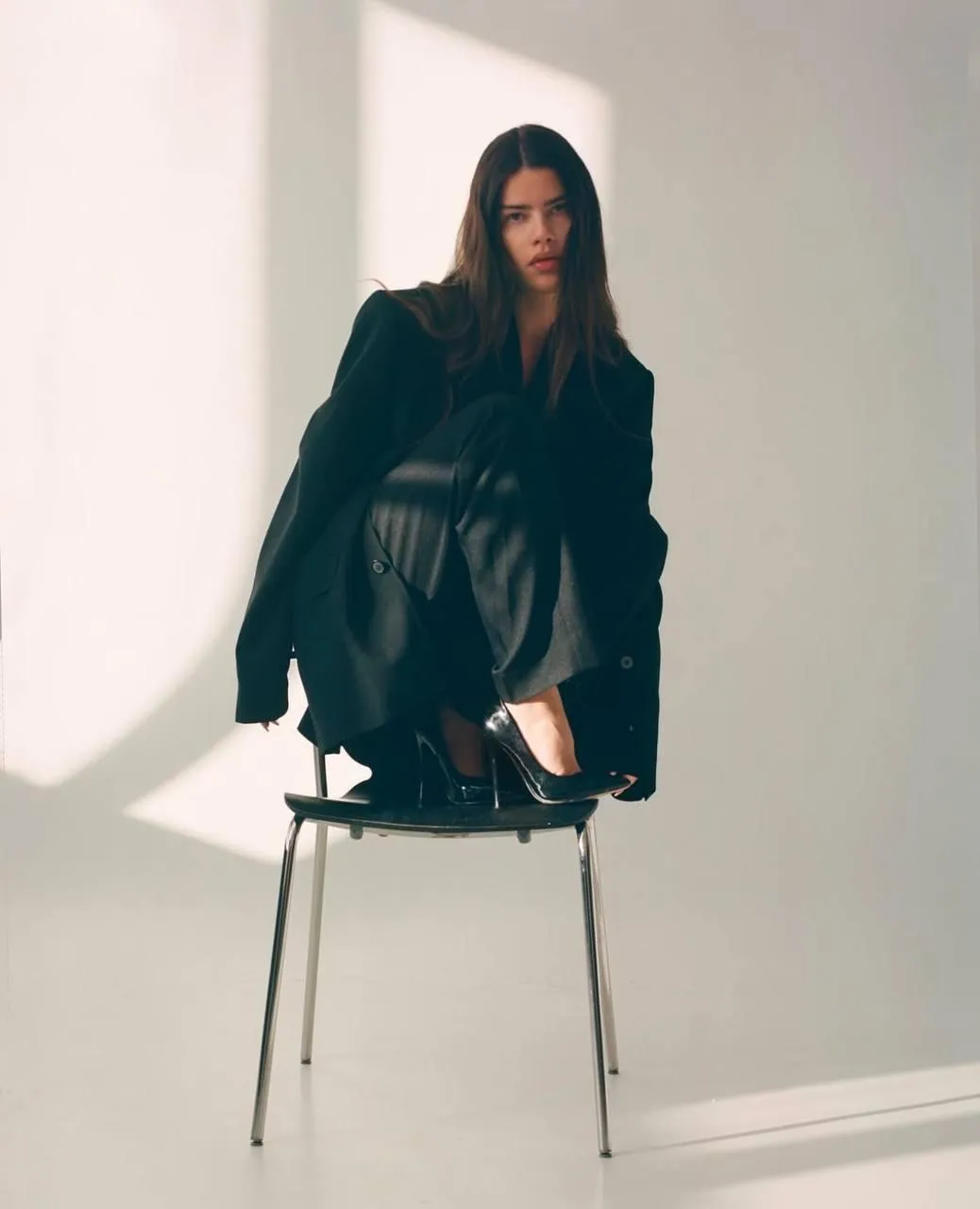 woman sitting on the chair with a black outfit and heels