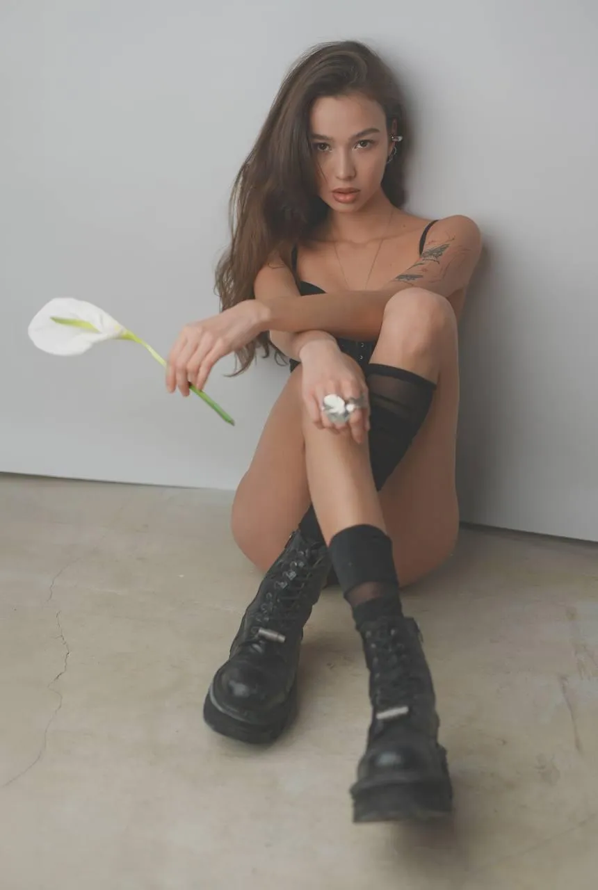 Woman sitting on the floor holding a flower free wallpaper