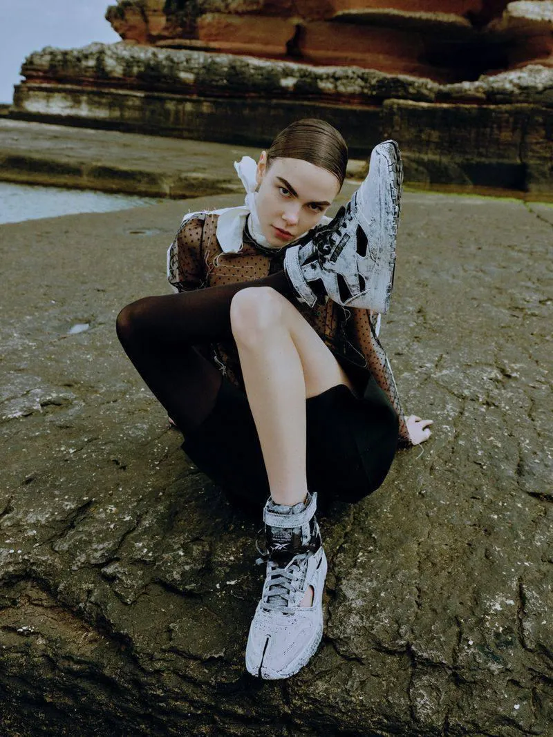 Woman Sitting on the Rocky Terrain Wearing Trendy Sneakers