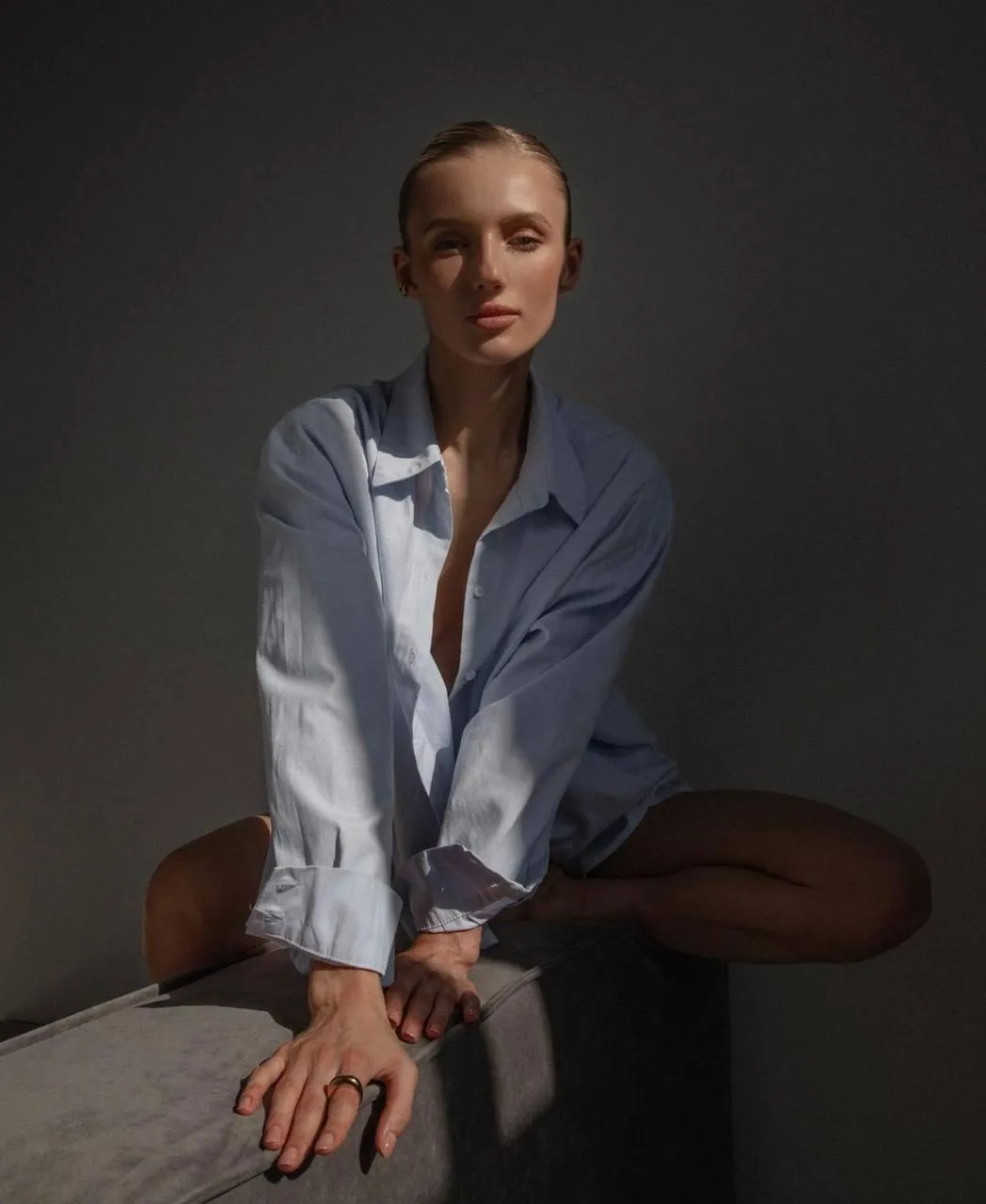 Woman sitting with white shirt in a dramatic shadow lighting