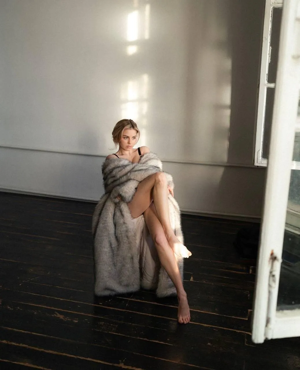 Woman Standing in Soft Light Wrapped in a Cozy Nude Coat