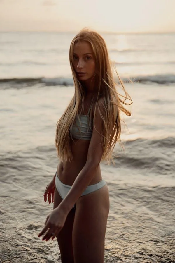 Woman standing on the beach wearing a bikini under sunlight