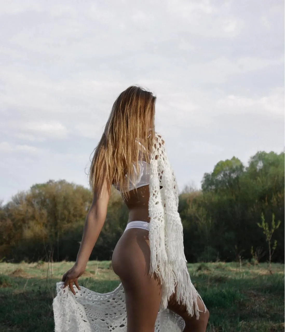 Woman Standing Outdoors in a White Outfit Looking at Nature