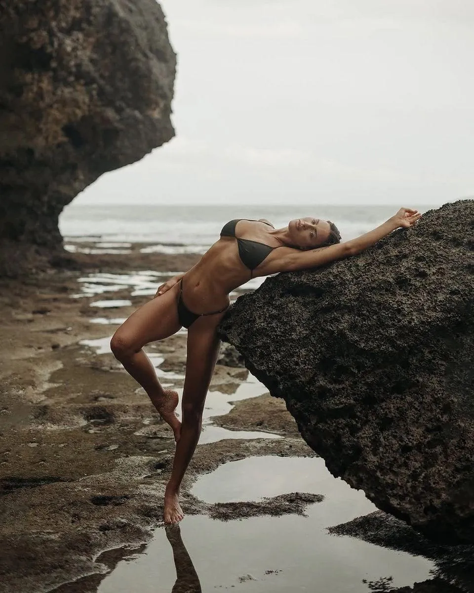Woman Stretching on Rocks by the Ocean with Brown Swimsuit