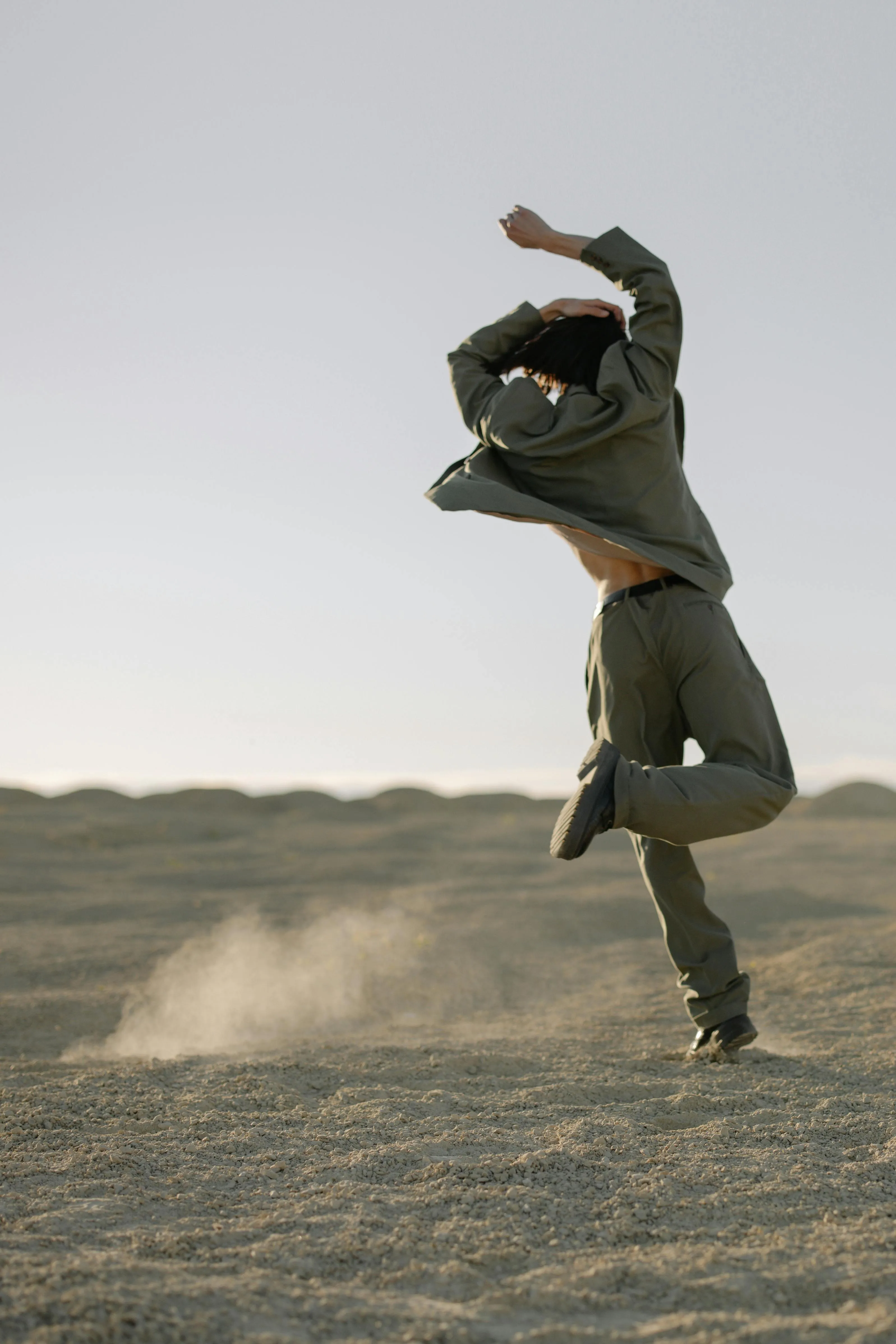 Woman Striking Dynamic Pose in a Flowing Outfit on the Sand