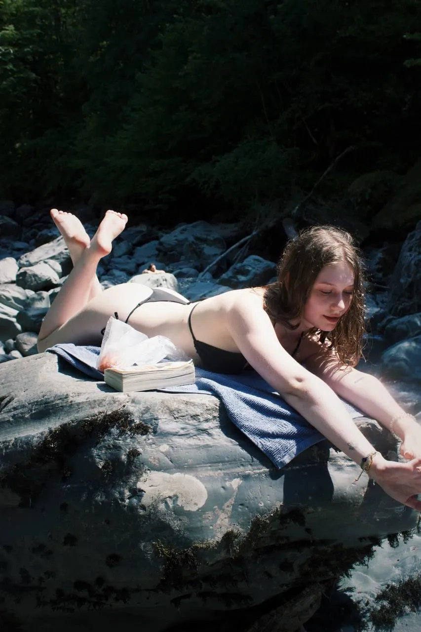 Woman Sunbathing on a Rocky Surface Near the Forest Stream