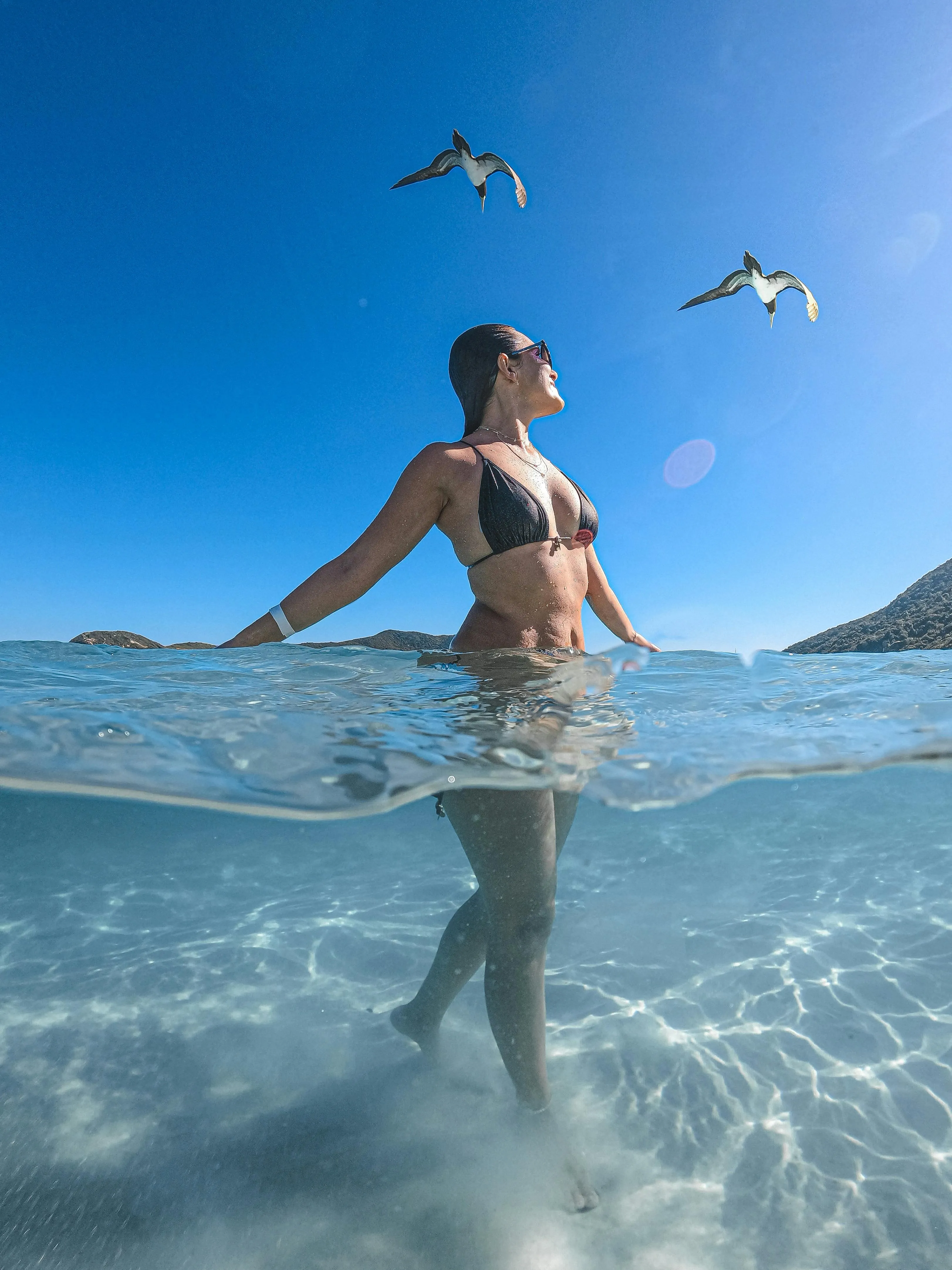 Woman Walking in Shallow Water Under a Blue Sky HD Wallpaper